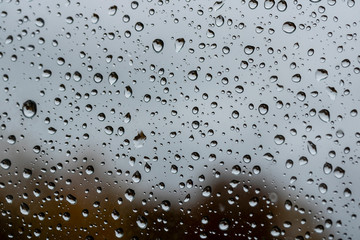 abstract drops on a window glass with blurred background close up , rain macro