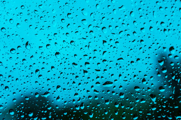 abstract drops on a window glass with blue background close up , rain macro