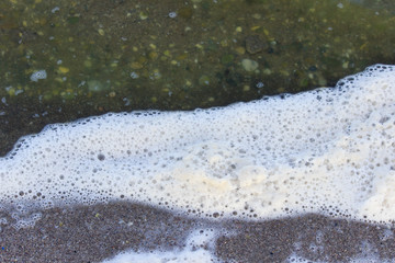 sea foam and green water in the sea lagoon. the lagoon is a bay separated from the sea. the color of water is due to special microflora