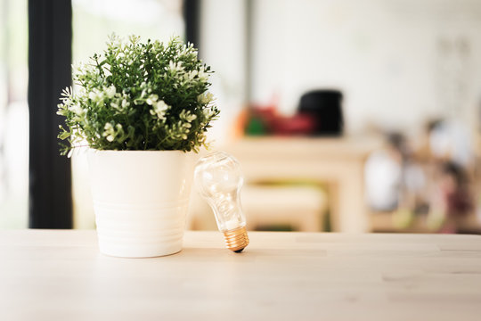 Light Bulb With White Flower And Green Leave On Wood Table, Business Solution,planning Ideas.glowing Contents, Creativity Inspiration And Save The Earth And Ecological Concepts.