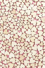 Celebtate greeting card with many small wooden hearts on pink paper surface. Love concept. Top view and flat lay. Vertical format.