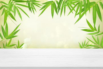 white wooden table top with beautiful green bamboo leave background for advertisement display