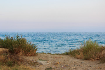 access to the sea. road and grass growing on the sidelines. pink and blue sky at pre-sunset hour
