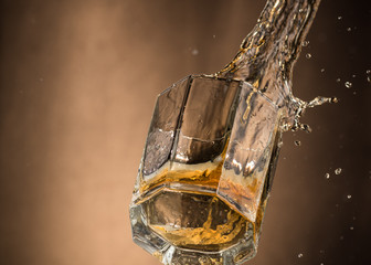 falling glass with whiskey and spray on a brown background