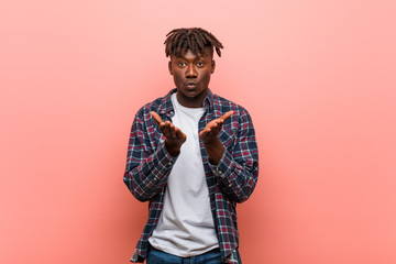 Fototapeta premium Young african black man folding lips and holding palms to send air kiss.
