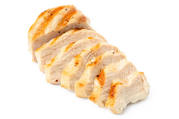 Partially sliced grilled chicken breast with grill marks, ground black pepper and salt isolated on white.