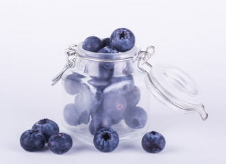 Delicious blueberries in a glass jar on white background.