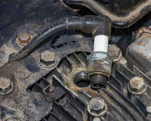 Closeup of spark plug removed from small gas engine on lawn mower. Concept of home dyi maintenance, tune-up, and repair