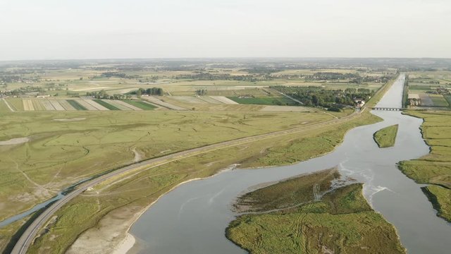 Aerial view of large river surrounded by agriculture fields against grey cloudy sky. Action. Aerial view of rural landscape.