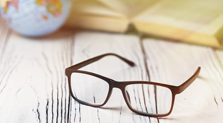 Glasses and a book on a wooden table. Vision problems.