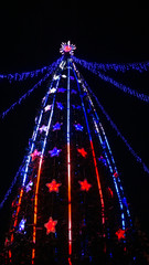 Obraz premium Christmas tree with lights on black background at night vertical photo