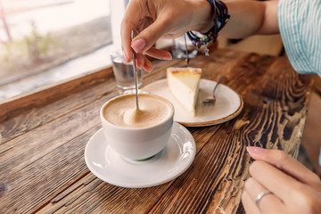 A Cup of cappuccino with foam in the shape of a heart and a piece of cheesecake on a vintage wooden background in a cafe