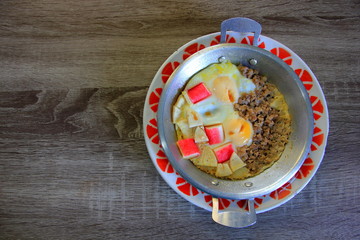 Top view fried eggs in a pan with Pork Chops and crab stick on gray table. 