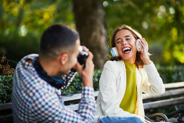 Young man photographing young woman with headphones for social network