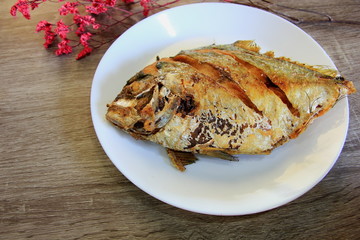 Fried fish in a white plate on the gray table.