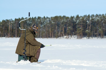 Fototapeta na wymiar man fishing in winter on an icy lake. Winter sport winter fishing
