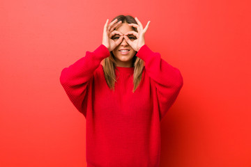 Fototapeta premium Young authentic charismatic real people woman against a wall showing okay sign over eyes