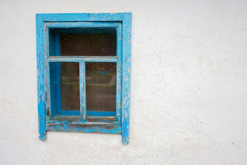 Old rustic window with a blue frame on a white wall background