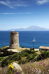 Fototapeta na wymiar Vista panorámica de la torre de Guadalmesí y un velero navegando por el estrecho de Gibraltar de fondo, Tarifa, Cádiz, Andalucía, España