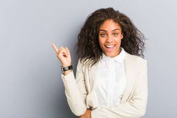 Young african american business woman smiling cheerfully pointing with forefinger away.