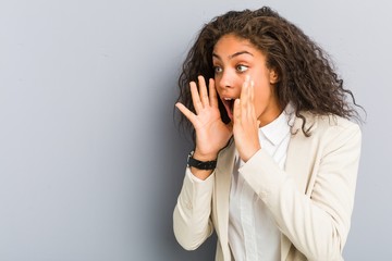 Young african american business woman shouts loud, keeps eyes opened and hands tense.