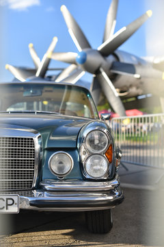 Kiev / Ukraine - 04.28.18: half front Mercedes-Benz 300 SEL 6.3 on background a turboprop aircraft with natural vignetting on the sides from white fence