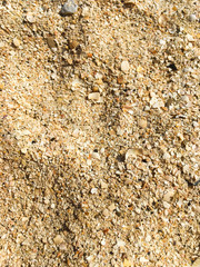 Yellow beach sand with small stones. Footprints in the sand.