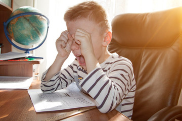 school-age boy crying and screaming while doing homework. the concept of heavy pressure education
