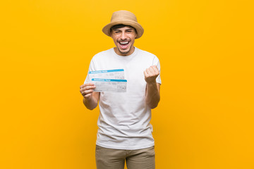 Young hispanic man holding an air tickets cheering carefree and excited. Victory concept.