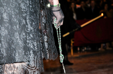 Mano de mujer con guante de rejilla agarrando rosario durante la noche en  jueves santo, Andalucía