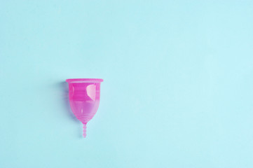 Menstrual cup on a blue background. Means of intimate hygiene of women. Free space for text.