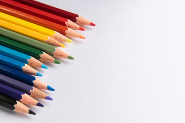 Colored pencils arranged in diagonal line on white paper background