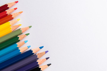 Colored pencils arranged in diagonal line on white paper background