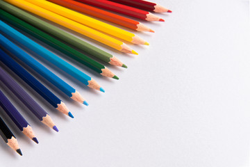 Colored pencils arranged in diagonal line on white paper background