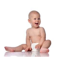 Happy infant child baby boy toddler in diaper is sitting  looking at something near him on copy...