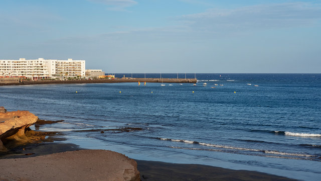 View of the volcanic beach towards the resort hotels, restaurants and terraces, in the bohemian village of El Medano in Granadilla de Abona, El Medano, Tenerife, Canary Islands, Spain