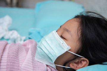 Obraz na płótnie Canvas little asian children girl wearing protective mask On the blue mattress in her bed room, she was not comfortable, flu and sleep