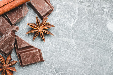 Chocolate cubes, star anise and cinnamon stick on grey textured background, top view