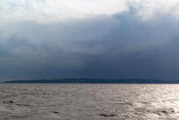 Dark blue clouds over water and coast