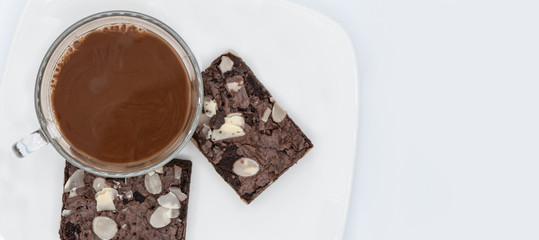 Cocoa drink in glass with chocolate macadamia nut brownie on white background.