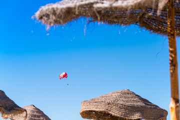 Fototapeta na wymiar Tourists on parasailing over the Mediterranean Sea near Djerba island, Tunisia. Tunisian flag printed on the parachute.
