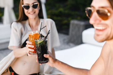 Smiling couple drinking cocktails at poolside