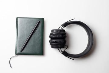 Pen on a notepad with a headphone on