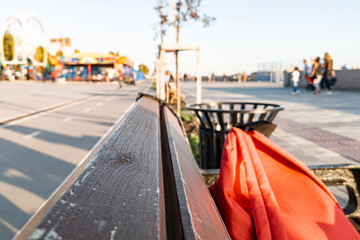 Close-up on wooden boards of a brown bench with a blurred background of a park on the promenade in the city on a warm summer day