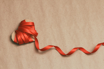 Satin red ribbon heart on craft paper. Background textures. Love. Postcard. Health insurance. Heart...