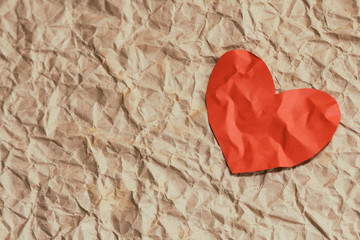 Paper red heart on crumpled craft paper. Background textures. Love. Postcard. Health insurance. Heart function test. Your text space.