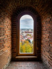 View through a window of the historic Gediminas tower across Old Town and a church in Vilnius Lithuania