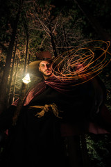 Wizard man with magic wand perform illusion in forest