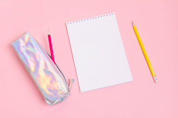 Mother of pearl pencil case, pink and yellow graphite pencils and a notebook on a pastel pink...