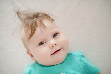 Naklejka premium Portrait of adorable baby girl with blue eyes and cute hair looking at the camera calmly with a smile; cute baby facial expressions and learning steps or motherhood and family and fertility concepts